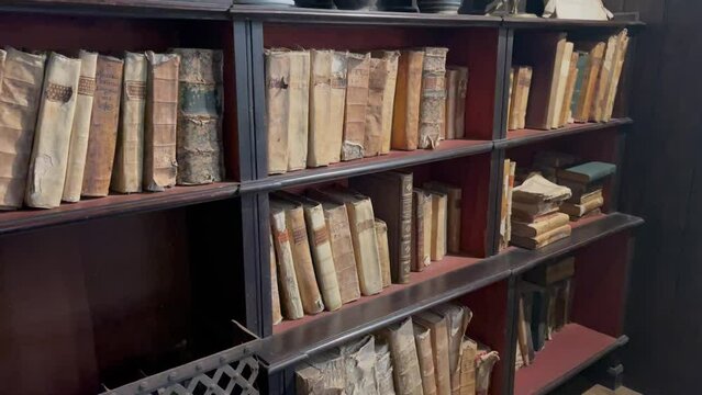 POV of ancient books on wooden shelves In an old library