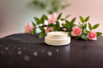 Obraz na płótnie Canvas A small transparent jar of face cream. AI generation. Face cream and pink roses.