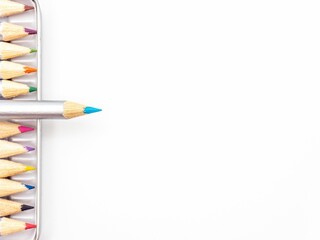 Vibrant array of colored pencils in a metal tin container against a white background