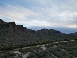 Aerial shot of flowing water surrounded by cliffs and a landscape covered with bushes