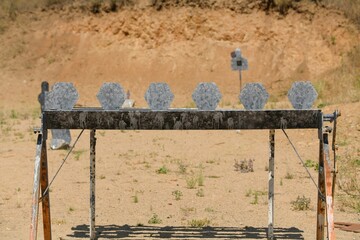 Targets at a shooting range set up in a desolate outdoor area illuminated by bright sunlight