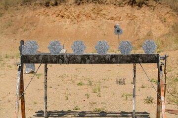 Targets at a shooting range set up in a desolate outdoor area illuminated by bright sunlight