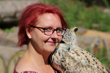 Portrait of a loving woman holding an owl outdoors