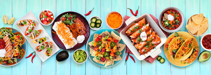 Mexican food table scene. Top down view on a blue wood banner background. Tacos, burrito plate,...