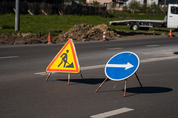 Blue and yellow-red safety signs warning about road works.The road is under construction or repair. Repair work in the middle of the carriageway, selective focus.
