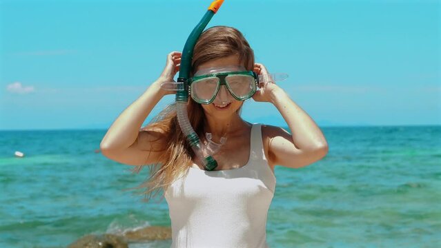 Woman in swimwear putting on snorkel mask, standing in sea water. Thailand travel, summer vacation. Concept of snorkeling adventure and tropical escape.