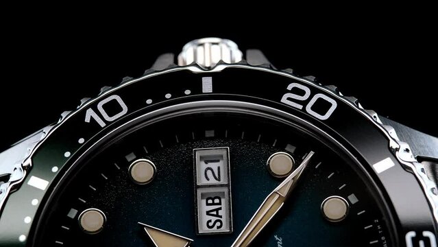 Extreme closeup of yellow second arrow passing by on blue clock face. Lengthwise view of luxury swiss watch. Closeup real time shot. Running second arrow