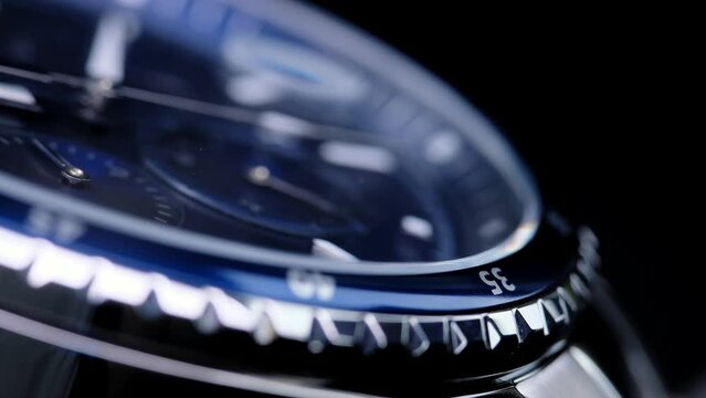 second hand ticking on a blue watch face. Men's chronograph watch in metal with sapphire crystal. closeup view of rotating watch, running second arrow. blue dial