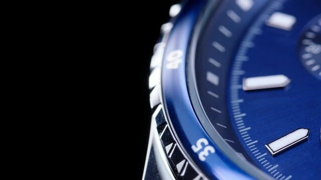 second hand ticking on a blue watch face. Men's chronograph watch in metal with sapphire crystal. closeup view of rotating watch, running second arrow. blue dial