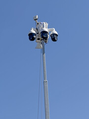 A lot cop crime prevention security camera array is shown above a retail store parking lot during the day in a vertical view.