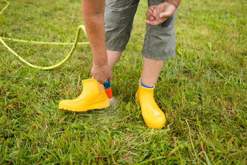 Washing of rubber boots. Close-up of a woman's hands washes yellow rubber boots from mud with a...