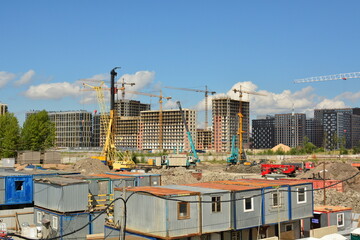 Fototapeta premium Construction site and construction city near the development of new residential buildings: building frames, construction machinery, tower cranes, сonstruction trailers.