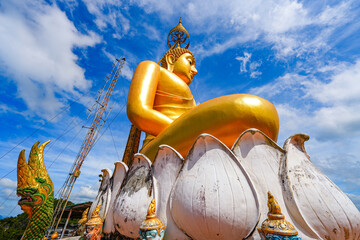 Giant golden statue of a Meditation Buddha in the lotus position overlooking Krabi mountains at the...