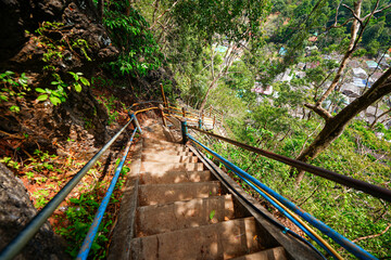 Fototapeta premium Steep stairs climbing up a limestone karst cliff through the rainforest to the mountaintop pagoda of the Wat Tham Suea aka the Tiger Cave Temple of Krabi in the south of Thailand