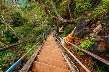 Steep stairs climbing up a limestone karst cliff through the rainforest to the mountaintop pagoda of the Wat Tham Suea aka the Tiger Cave Temple of Krabi in the south of Thailand