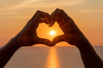 Hands heart sea sanset. Hands forming a heart shape made against the sun sky of a sunrise or sunset on a beach