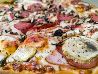 Big and tasty pizza on fat crust with a lot of toppings like pepperoni, champignons, sauce, cheese and aromatic spices