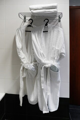 White bathrobes hanging in hotel. Close up of twins bathrobe