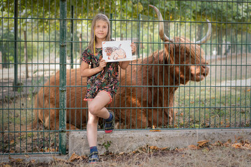 Child, young girl holding a sketchbook with a drawing of a highland cow, life drawing, she made in...