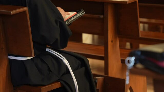 Fraile monje sacerdote padre franciscano meditando rezando leyendo orando con la biblia en una capilla de oraci&oacute;n en templo iglesia cat&oacute;lica cristiana conociendo la palabra de Dios
