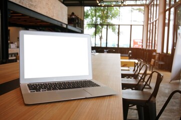 Laptop with Mock up blank screen on wooden table in front of coffeeshop cafe space for text. product display montage- technology concept