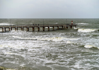 Tides and storms at sea. Sea pier. Waves on the Baltic Sea. Deserted seashore.
