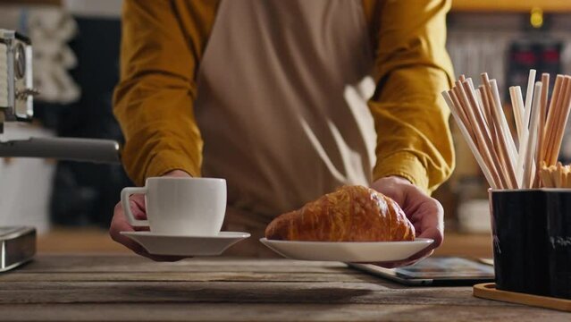 Takeaway food, coffee artist getting a croissant order at the counter in a coffee shop. The concept of bartender-coffee maker in the process of making coffee masters new recipes for making drinks shop