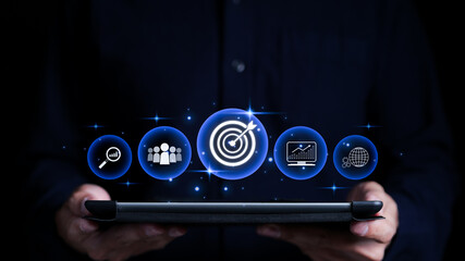 Targeting the business concept. Businessman holding tablet with business goal target icons on...
