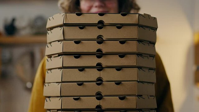 Baker waiter holding a pile of pizza cardboard boxes, Pizzeria master holding a stack of cardboard boxes ready to take away orders, receiving pizza orders. Background of pizza cardboard boxes