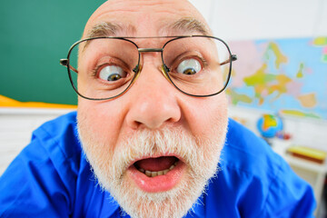 Closeup portrait of surprised teacher in glasses. Male teacher or professor in school classroom....