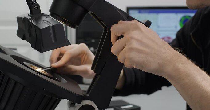 Specialist or gemologist looking through a microscope to examine diamond. Gem or diamond quality control or inspecting in the laboratory