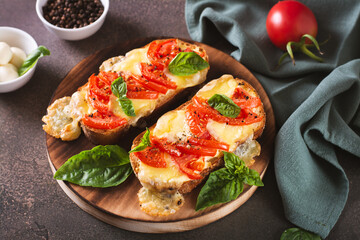 Baked brioche sandwiches with tomatoes, mozzarella and basil on a cutting board