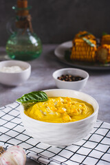 Delicious corn cream soup in a bowl on the table vertical view