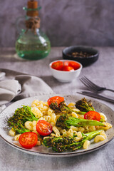 Pasta with cherry tomatoes and fried broccoli sprouts on a plate vertical view