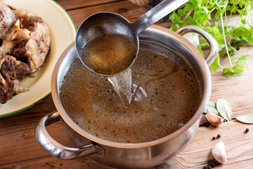 Beef Bone Broth in a glass jar, with fresh vegetables on wooden table
