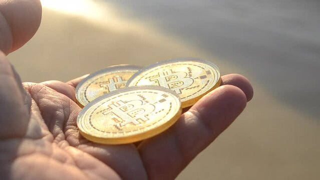 Man holding Bitcoin BTC coins in hand on background sea waves on sandy beach on sea shore on sunny day. Concept cryptocurrency money cryptography cryptocurrencies bitcoins. Peer-to-peer payment web 3