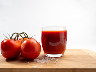 Glass of tomato juice and tomatoes on a white background. Freshly prepared tomato juice.
