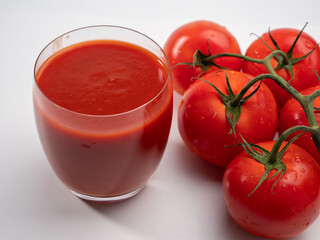 Glass of tomato juice and tomatoes on a white background. Freshly prepared tomato juice.