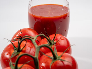 Glass of tomato juice and tomatoes on a white background. Freshly prepared tomato juice.