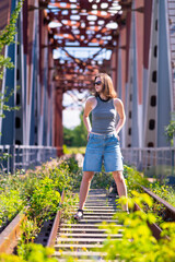The girl is standing among the railway tracks
