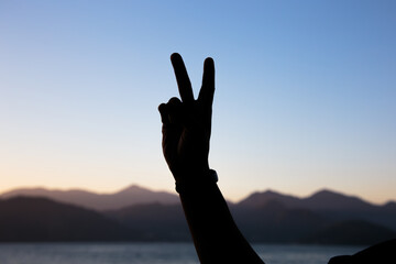 silhouette of hands in the shape of the number two with a beautiful colorful late afternoon sky in Rio de Janeiro.