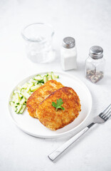 Fresh prepared schnitzel in a plate with fresh cucumber slices