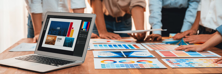 Graphic designer brainstorming logo and graphic art at busy artistic workshop, laptop display...