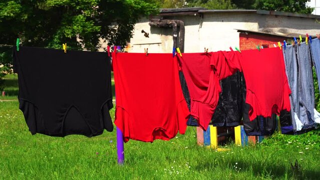 Drying colored laundry that hangs on a clothesline outside.