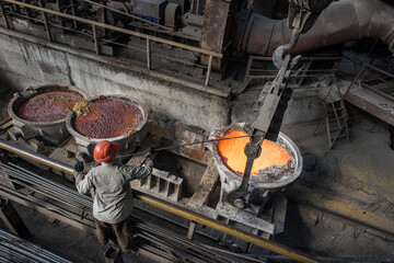 Steelworker at work near the tanks with hot metal - 631627447