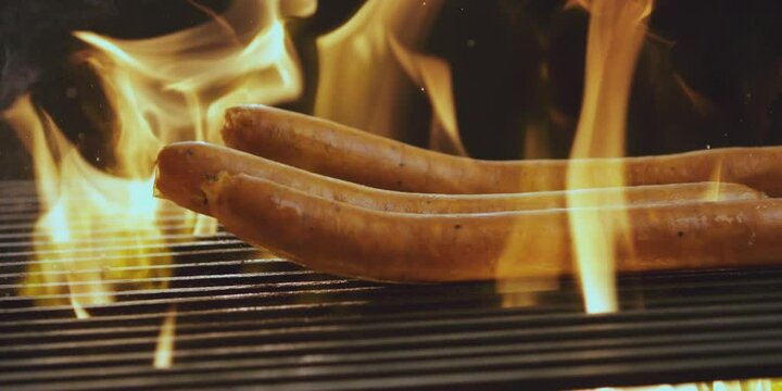 Slow-motion shot of hot dogs falling on the grill machine. Cooking hot dogs with meat products 