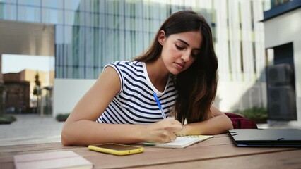Inspired hispanic woman studying and writing notes at the University - Student girl thinking and working on project 