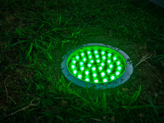Turned on green light. Street illumination lamp in the ground. Lantern in the ground. Palm lighting.