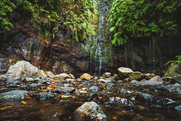 Naklejka na ściany i meble Scenic view of green overgrown 25 Fontes waterfall with stones and water in the foreground. 25 Fontes waterfalls, Madeira Island, Portugal, Europe.