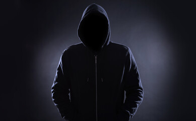 Anonymous man in hood on black background